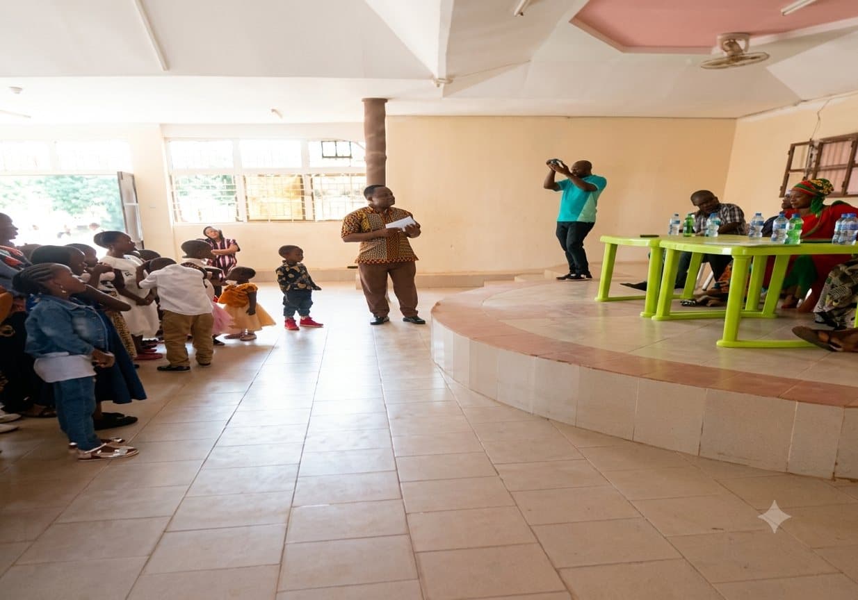 A UPSDE community session in progress, with families and children gathered in a hall in Mwanza