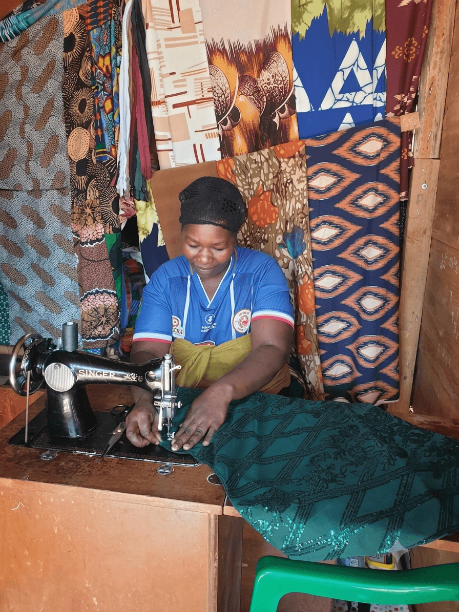 A young woman operating a sewing machine surrounded by fabrics during a UPSDE tailoring apprenticeship
